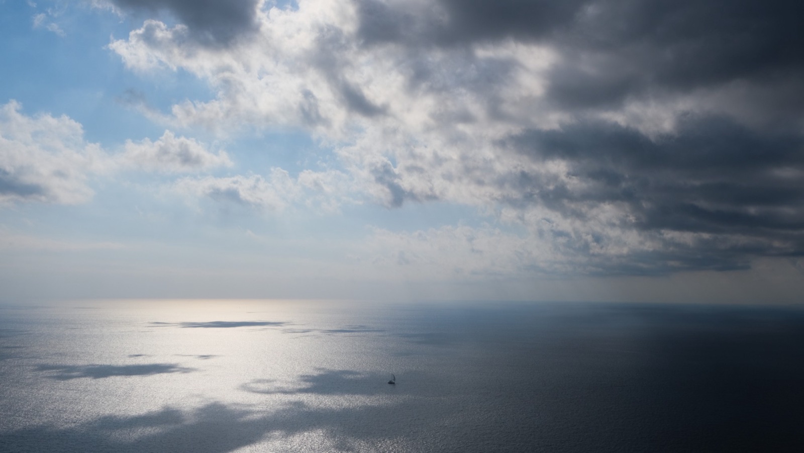 Sunlight breaking through storm clouds onto open water.